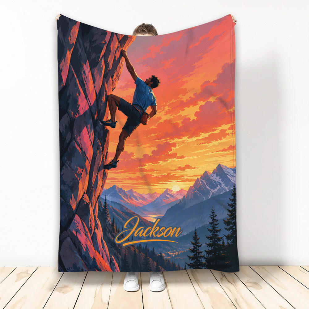 Rock climbing blanket featuring a climber on a sunset cliff above a dramatic mountain landscape