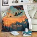 Rock climbing throw blanket displayed on a sofa with a sunset climber and mountain artwork