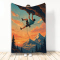 Rock climbing blanket featuring a climber on an overhanging cliff above a sunset mountain landscape