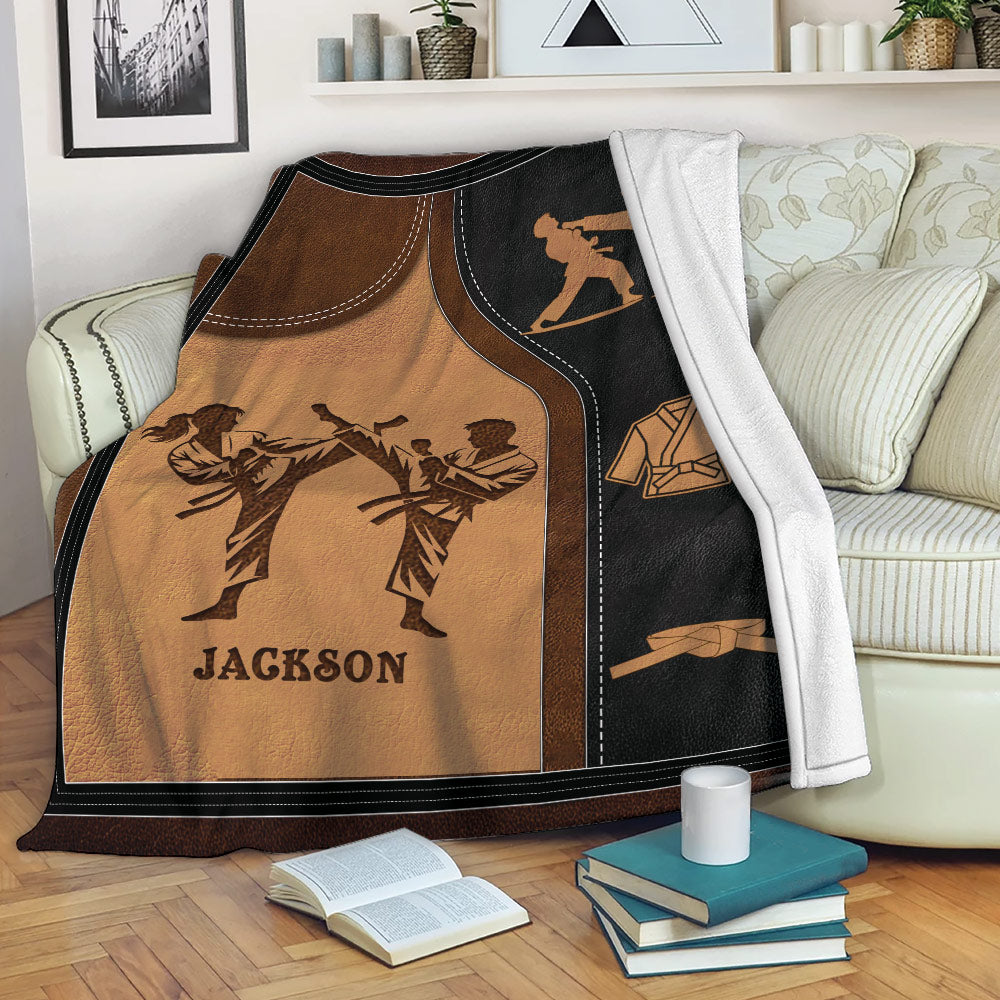 Taekwondo throw blanket displayed on a sofa with martial arts figures, uniforms, and belt-themed artwork
