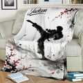 Taekwondo throw blanket displayed on an armchair with high-kick artwork and Japanese ink-inspired blossoms