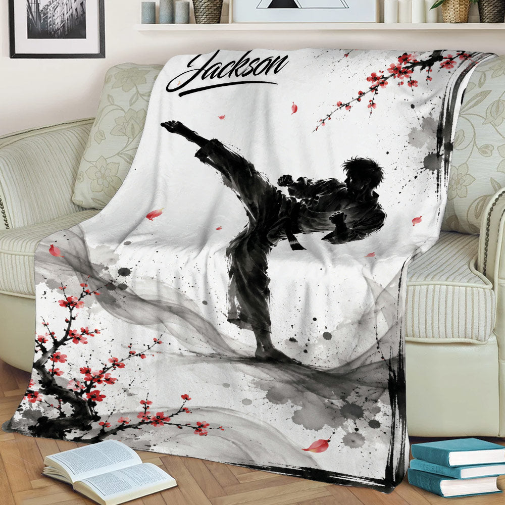 Taekwondo throw blanket displayed on an armchair with high-kick artwork and Japanese ink-inspired blossoms