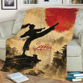 Taekwondo throw blanket displayed on a couch with martial artist silhouette, red sun, and mountain scenery