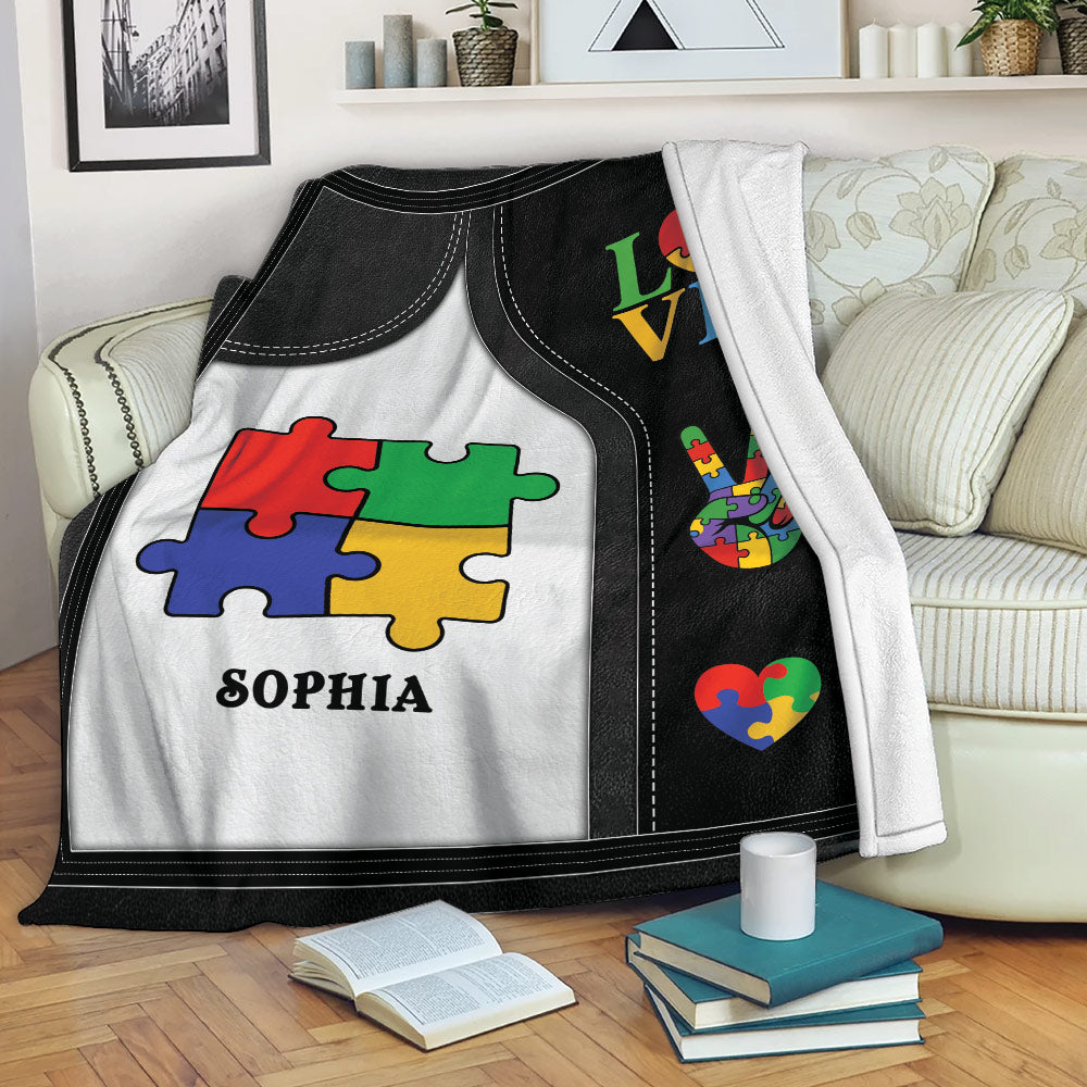 Autism throw blanket draped over a sofa with colorful puzzle-piece artwork and heart designs