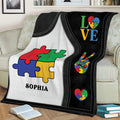 Colorful autism puzzle-piece throw blanket displayed on a sofa with bold black-and-white artwork