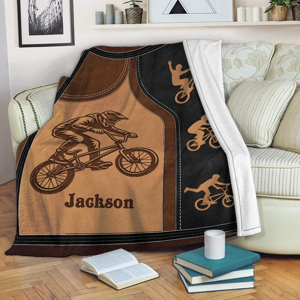 BMX throw blanket displayed on a sofa with freestyle bicycle rider artwork and black border