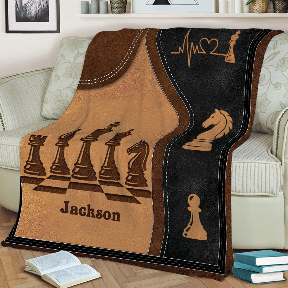 Chess blanket displayed on a sofa with a chessboard pattern, sculpted chess pieces, and elegant dark artwork