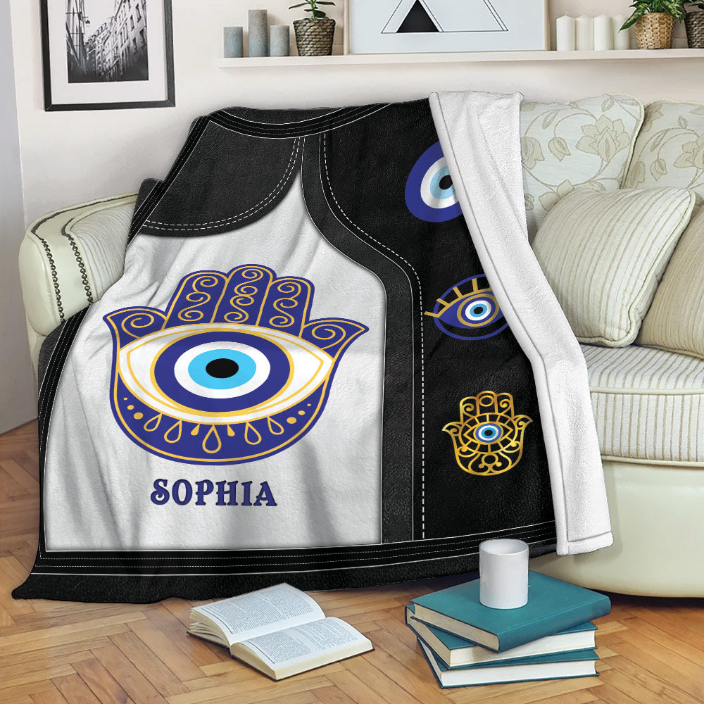Evil Eye blanket draped over a sofa with Hamsa hand and protective eye designs