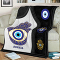 Black and white Evil Eye throw blanket displayed on a couch with blue and gold artwork