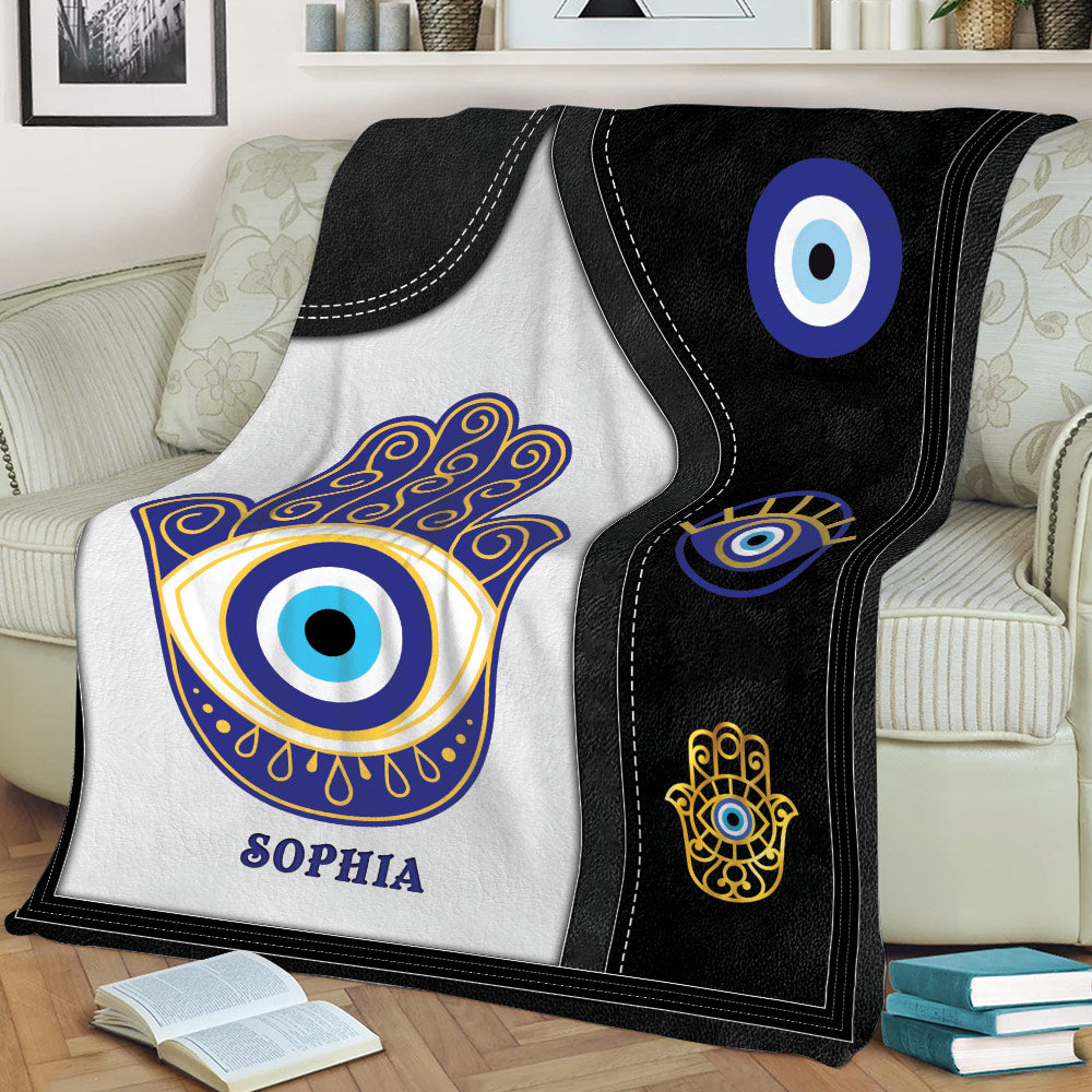 Black and white Evil Eye throw blanket displayed on a couch with blue and gold artwork