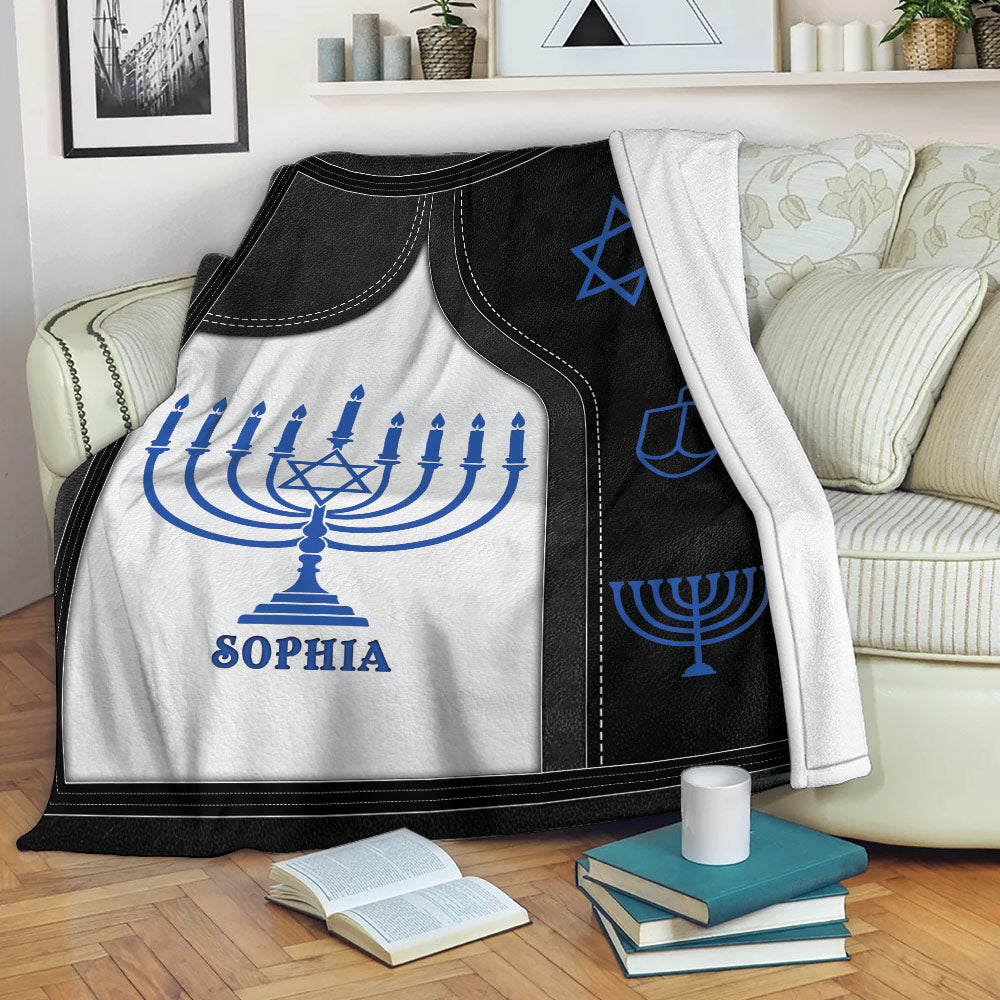 Hanukkah throw blanket draped over a sofa with blue menorah and Star of David designs