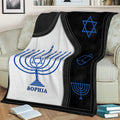 Close view of a Hanukkah blanket featuring menorah artwork, a Star of David, and dreidel