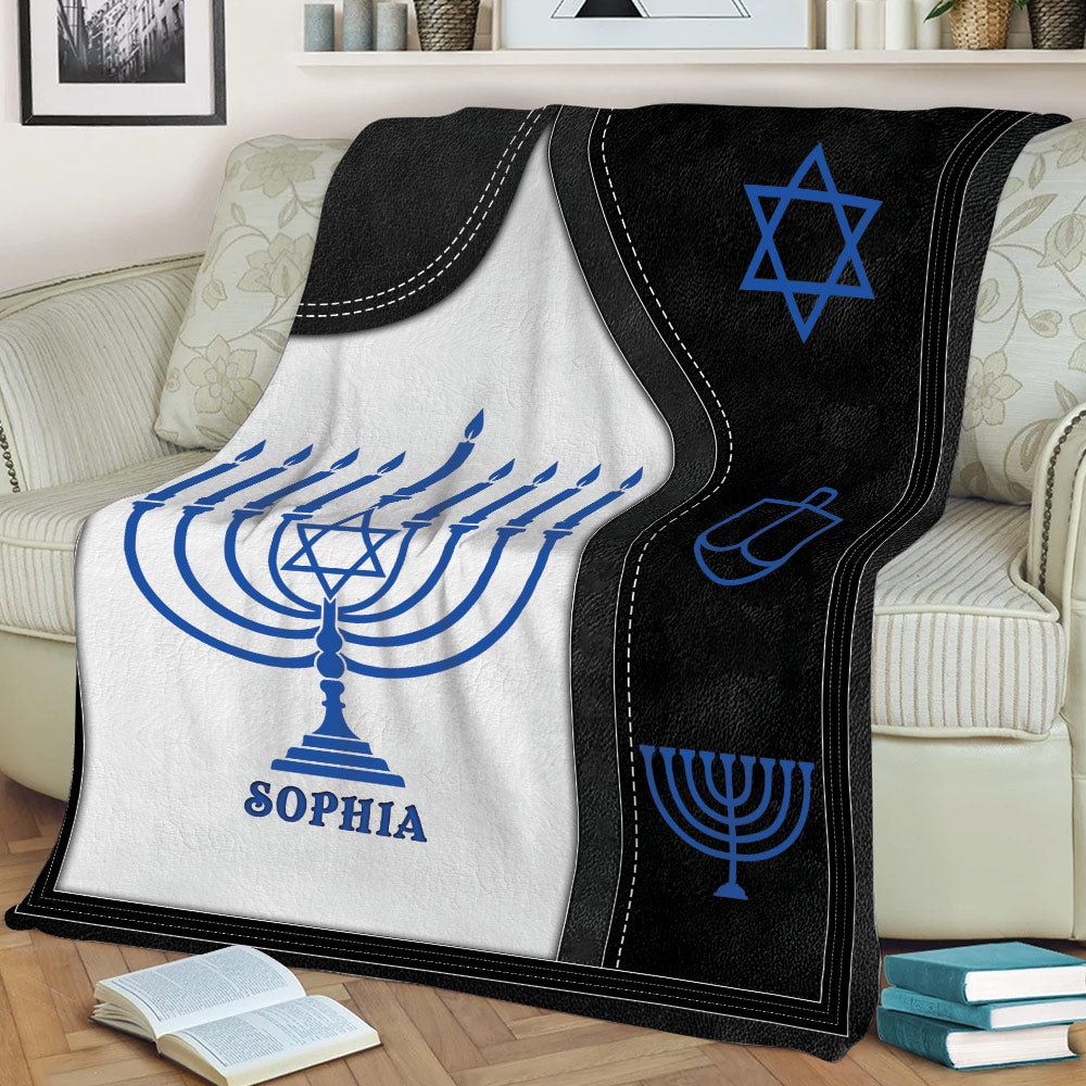 Close view of a Hanukkah blanket featuring menorah artwork, a Star of David, and dreidel