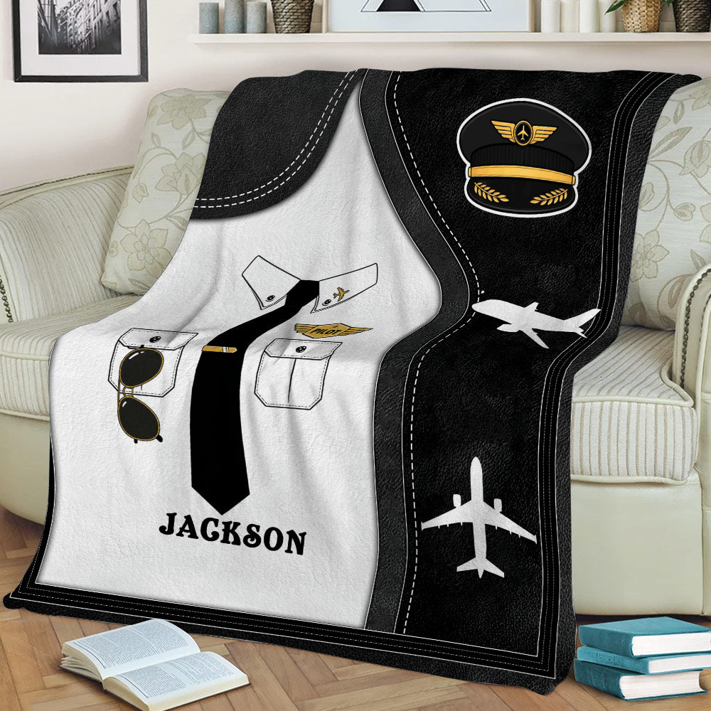 Close lifestyle view of a pilot throw blanket with captain hat artwork, uniform details, and airplane graphics
