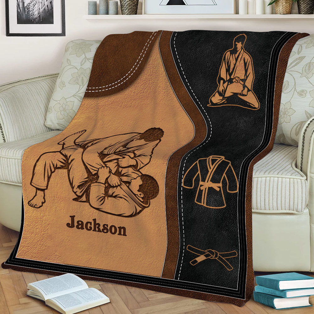Jiu Jitsu blanket draped over a sofa, featuring grapplers, a martial arts uniform, and belt artwork