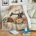 Sewing-themed throw blanket displayed on a sofa with a vintage machine, flowers, lace, and fabric artwork
