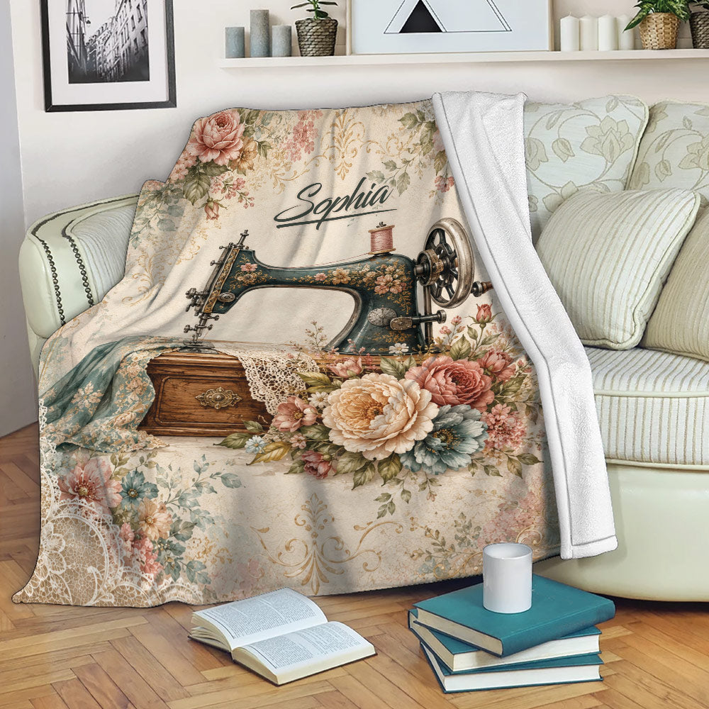 Sewing-themed throw blanket displayed on a sofa with a vintage machine, flowers, lace, and fabric artwork