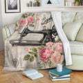 Sewing throw blanket with vintage sewing machine artwork and pink roses draped across a cozy living room sofa