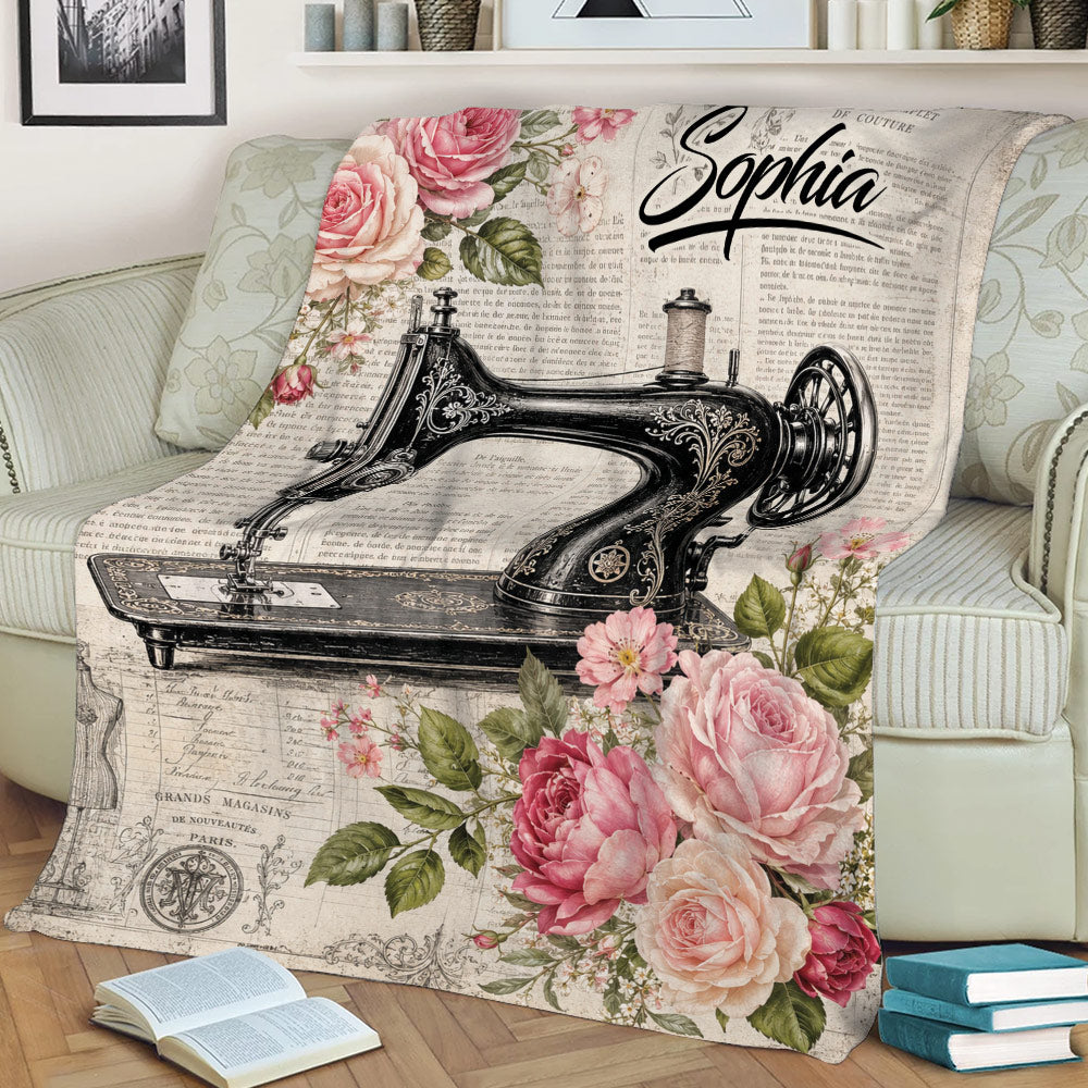 Vintage sewing machine throw blanket with floral rose artwork styled on a sofa beside books