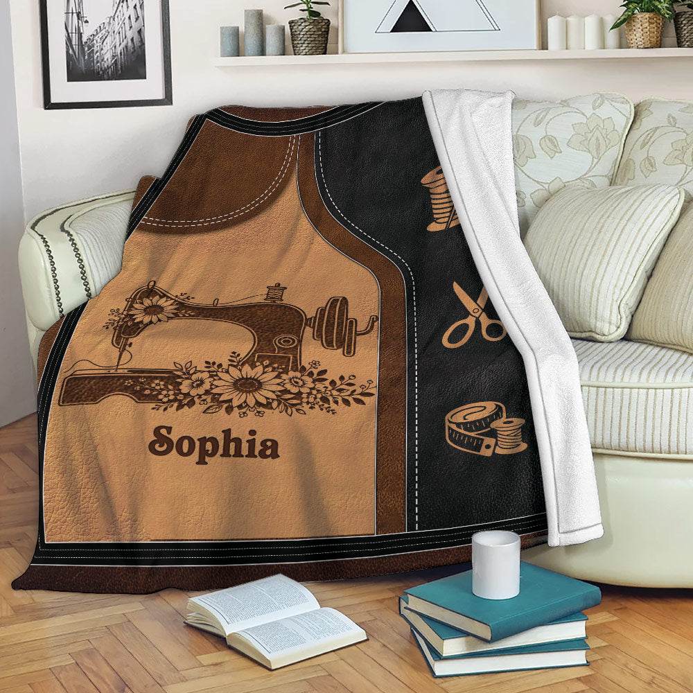 Sewing throw blanket styled on a sofa with floral sewing machine artwork and tailoring symbols