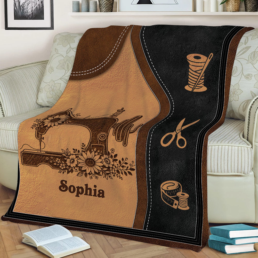 Close view of a sewing blanket with vintage-inspired sewing machine, scissors, thread, and floral artwork