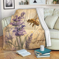 Bee throw blanket draped over a sofa with purple flowers, vintage script, and botanical artwork