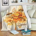 Bee throw blanket displayed on a sofa with watercolor honeycomb, flowers, honey, and honeybee artwork