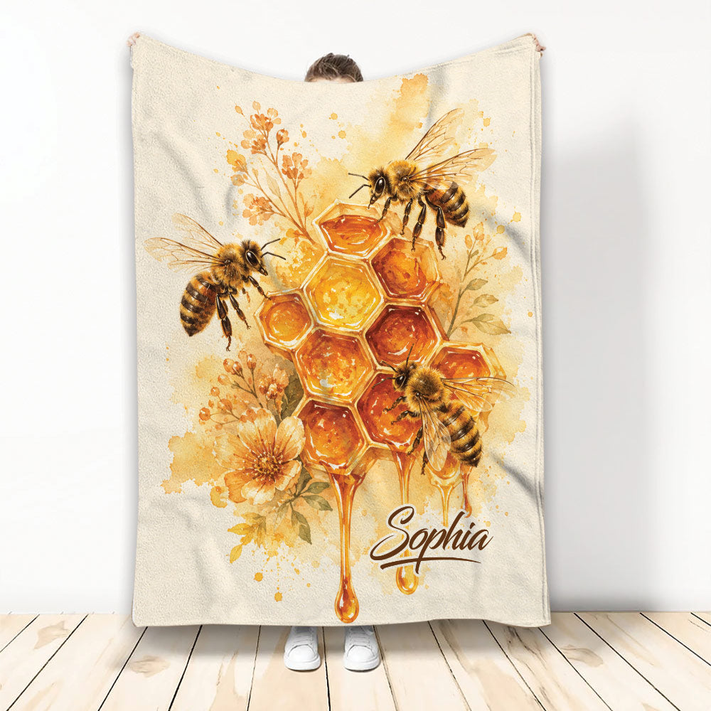 Bee blanket with watercolor honeycomb, honey drips, flowers, and three honeybees in warm golden tones