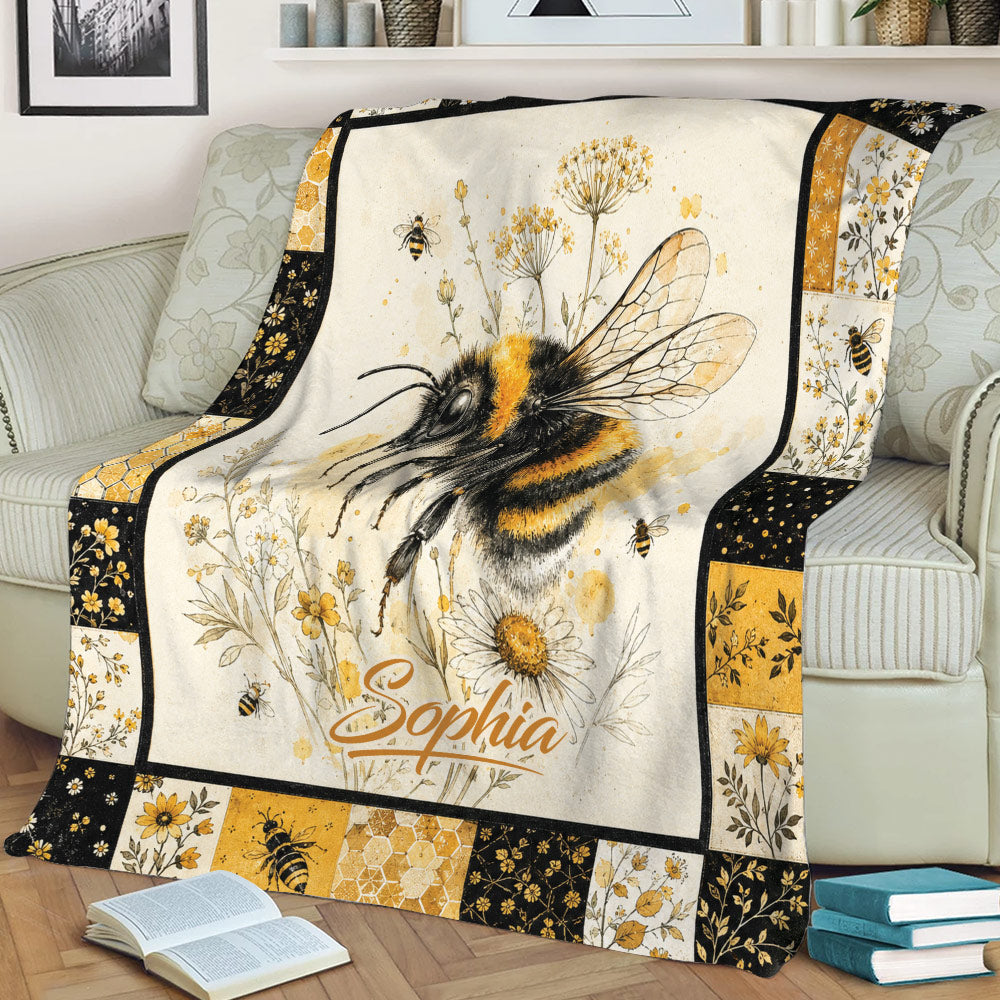 Honeybee throw blanket displayed on a sofa with botanical flowers, honeycomb details, and golden floral borders