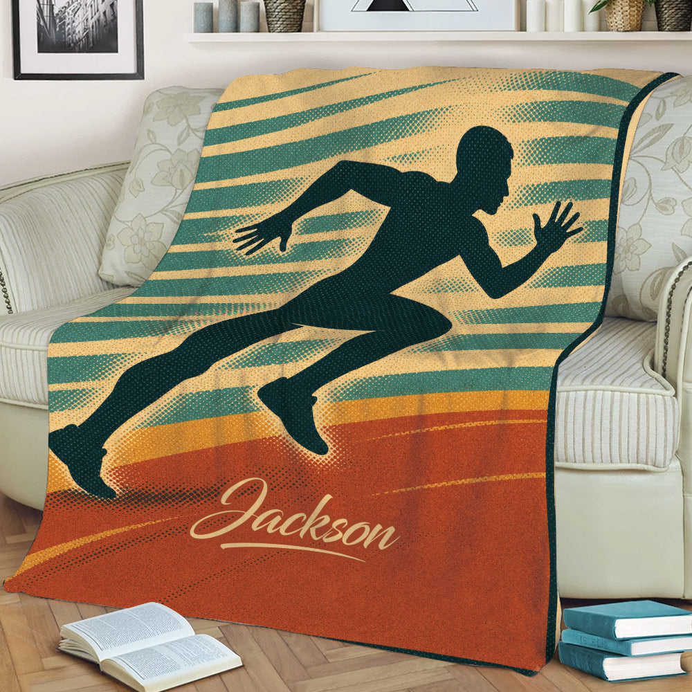 Running throw blanket displayed on a couch with bold motion lines and a sprinting athlete design