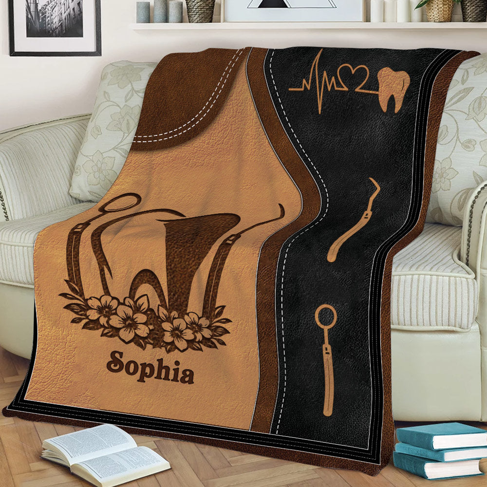 Close view of a dental-themed blanket with tooth, dental tools, and floral artwork
