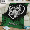 Green ATV blanket displayed on a sofa with graphic quad rider artwork and rugged tire-track details