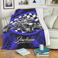 Blue and black ATV throw blanket displayed across a sofa with quad rider and checkered flag artwork