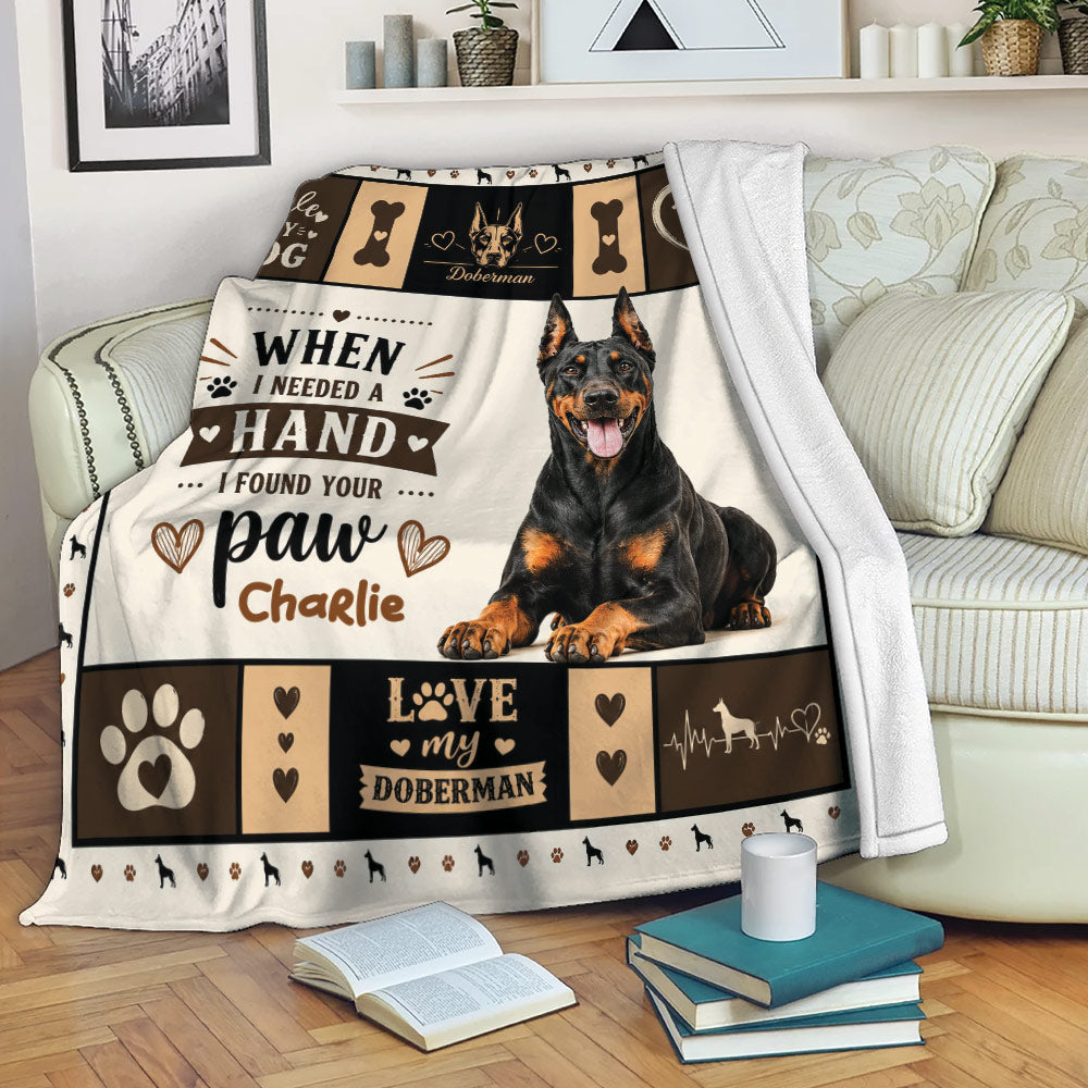 Doberman throw blanket displayed on a sofa with black and tan dog artwork and warm dog lover decor
