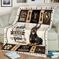 Close lifestyle view of a Doberman blanket featuring a realistic dog, paw prints, hearts, and bold typography