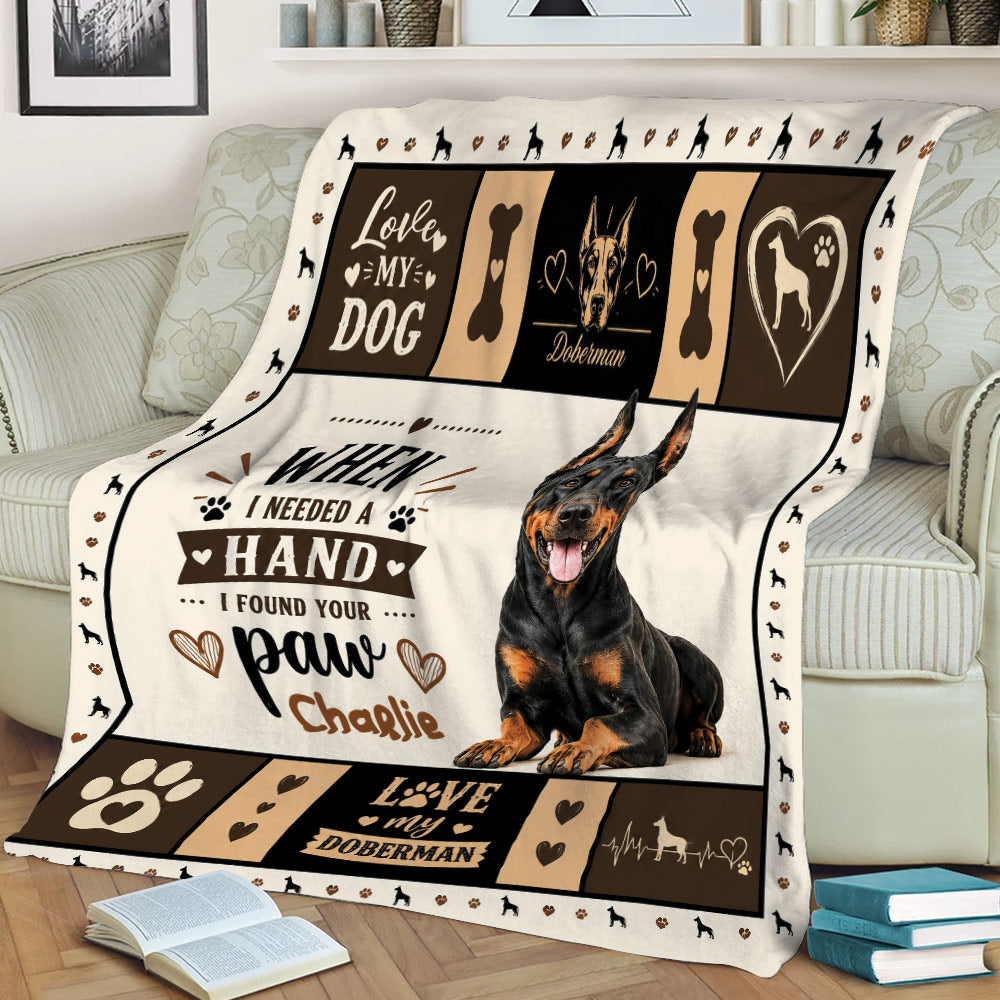 Close lifestyle view of a Doberman blanket featuring a realistic dog, paw prints, hearts, and bold typography