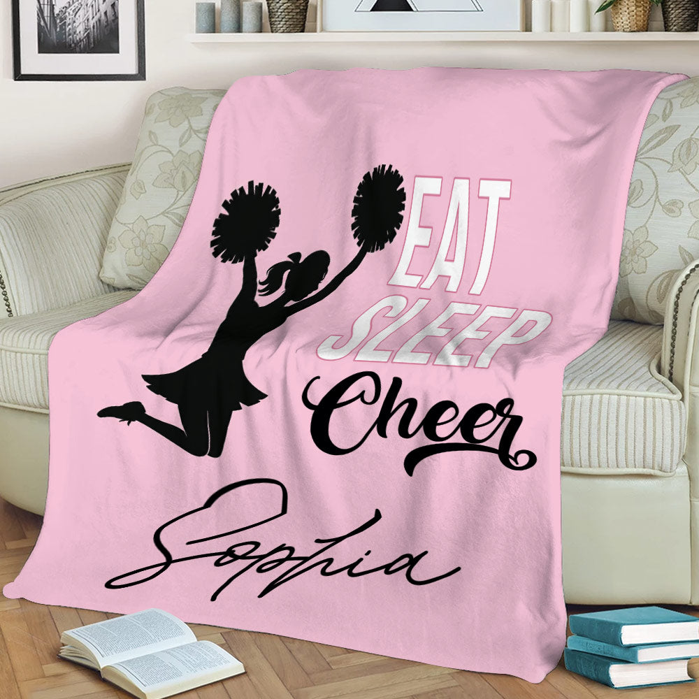 Cheerleading throw blanket displayed on a couch with pink artwork and pom-pom silhouette