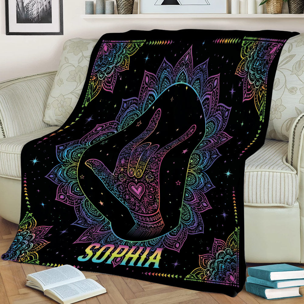 Colorful sign language hand gesture blanket draped over a couch with vibrant mandala design