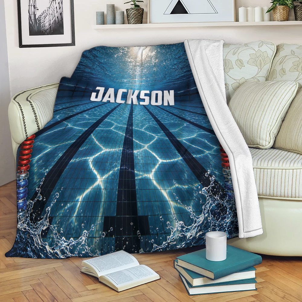 Swimming throw blanket displayed on a sofa with blue pool lane artwork and splashing water details