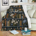 Book lover throw blanket draped over a sofa beside open books and stacked novels