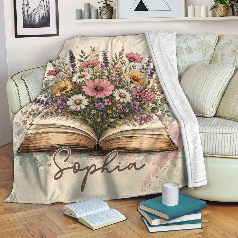 Book-themed throw blanket with floral artwork draped over a sofa in a cozy reading space