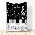 Black and white piano throw blanket with keyboard keys, musical notes, and treble clef artwork