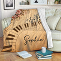 Piano throw blanket draped over a sofa with musical notes, curved keys, and vintage floral artwork