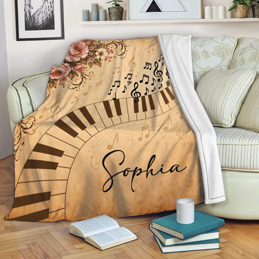 Piano throw blanket draped over a sofa with musical notes, curved keys, and vintage floral artwork