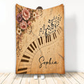 Vintage piano blanket with curved keyboard, musical notes, treble clefs, and ornate floral artwork