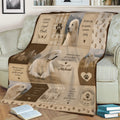 Great Pyrenees throw blanket displayed on a couch with multiple dog scenes, mountain illustrations, and paw print accents