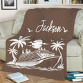Brown cruise ship blanket displayed on a sofa with tropical palms, waves, and coastal artwork