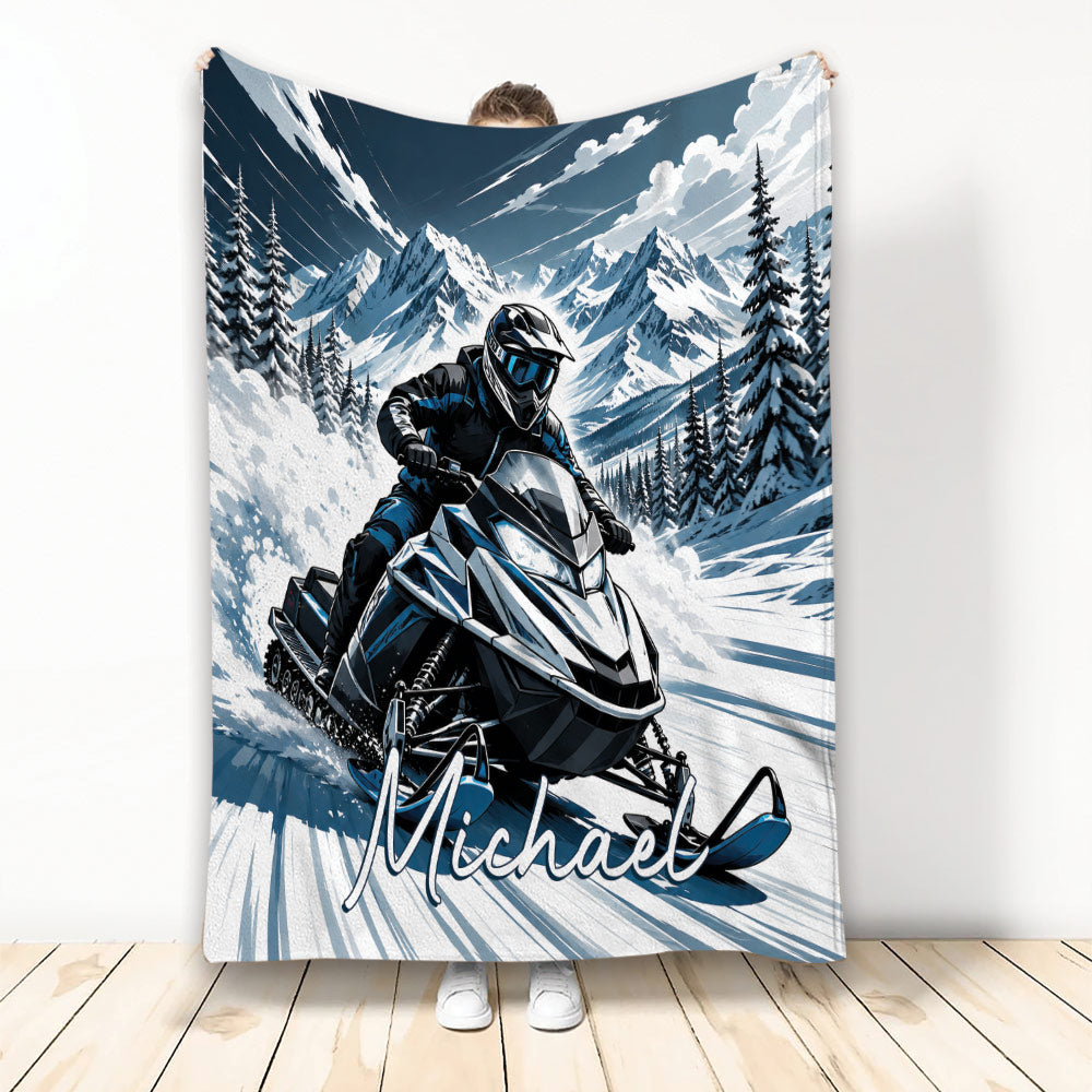 Snowmobile throw blanket featuring a helmeted rider on a mountain trail with snowy peaks and evergreen trees