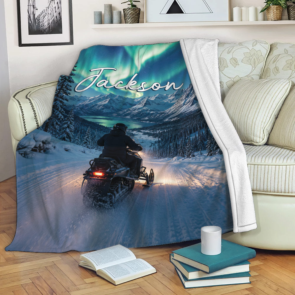 Snowmobile throw blanket draped over a sofa with snowy mountain scenery and aurora artwork