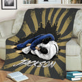 Jiu Jitsu throw blanket draped over a couch, featuring two grapplers and distressed black and gold design